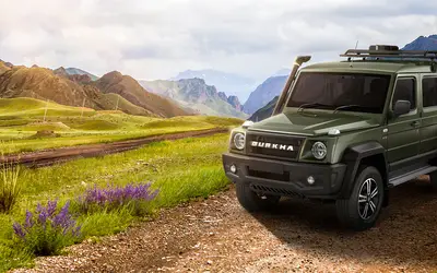 Force Gurkha five-door front three-quarter view in green on a mountain trail