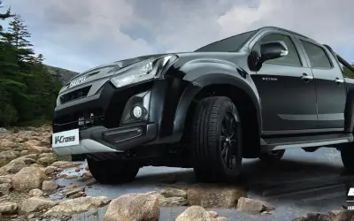 Isuzu D-Max V-Cross front three-quarter view in black over a rocky riverbed
