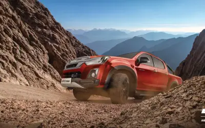 Isuzu D-Max V-Cross front three-quarter view in red climbing a dirt trail