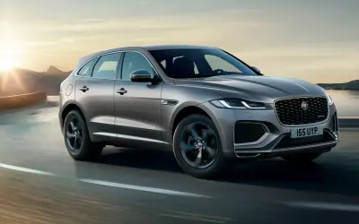 Jaguar F-Pace front three-quarter view in grey on a lakeside road at sunset