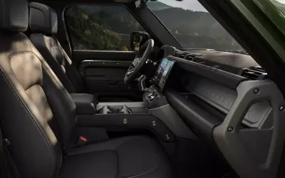 Land Rover Defender front cabin with the exposed structural cross-beam and central touchscreen