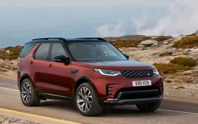 Land Rover Discovery front three-quarter view in red on a hillside road