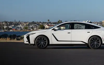 Lexus ES side profile in white on a waterfront road