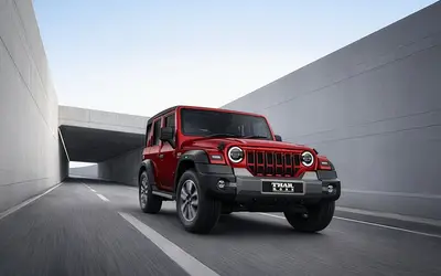 Mahindra Thar Roxx in red driving through a concrete underpass