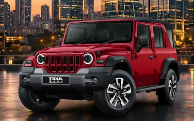 Mahindra Thar Roxx front three-quarter view in red against a city skyline at night