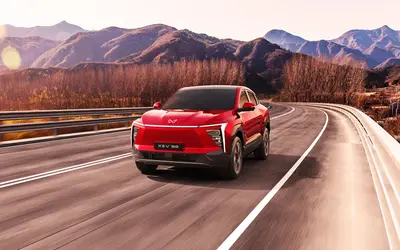 Mahindra XEV 9e front three-quarter view in red driving through mountains