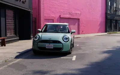 MINI Cooper 3-door in light green with a white roof, front three-quarter view on a city street