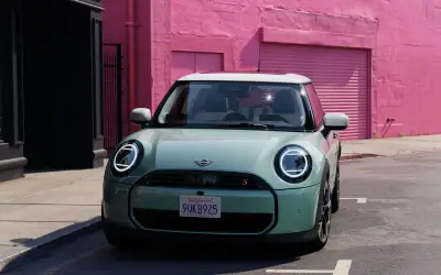 MINI Cooper 3-door in light green seen head-on, showing the round headlights and octagonal grille