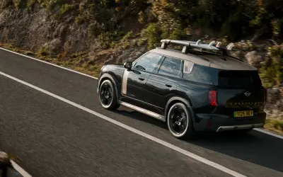 MINI Countryman Electric with roof rails on a mountain road, rear three-quarter view