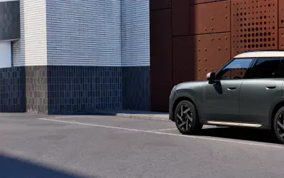 MINI Countryman in grey-green, side view alongside a textured facade