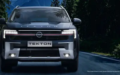 Nissan Tekton front view with illuminated grille on a forest road