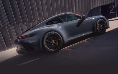 Porsche 911 Carrera GTS rear three-quarter view in grey alongside a ribbed wall