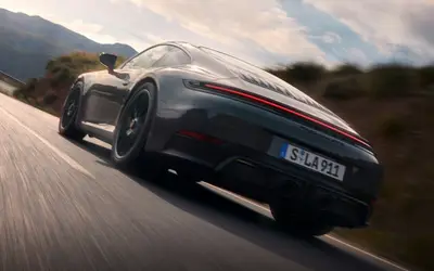 Porsche 911 Carrera GTS in grey driving away on an open road