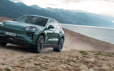Porsche Cayenne Electric in dark green, front three-quarter view on a mountain track