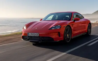 Porsche Taycan in red, front three-quarter view on a coastal road