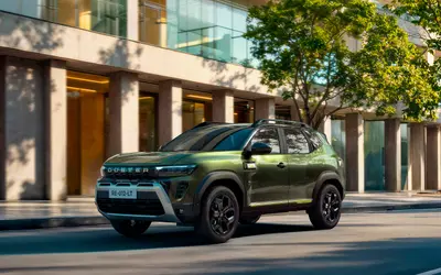 Renault Duster 2026 front three-quarter view on a city street showing the DUSTER-lettered grille and Y-shaped DRLs