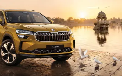 Skoda Kodiaq front three-quarter view in golden yellow at a lakeside at sunset