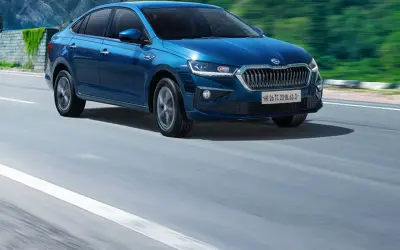 Skoda Slavia side profile in blue driving on a mountain highway
