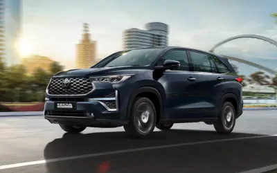 Toyota Innova Hycross in dark blue driving on a city road, front three-quarter view