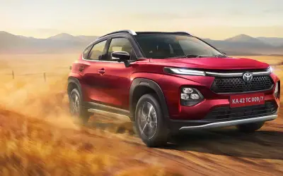 Toyota Urban Cruiser Taisor in red driving on a country road, front three-quarter view