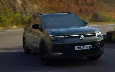 Volkswagen Taigun GT Line front three-quarter view in dark green, driving on a hill road