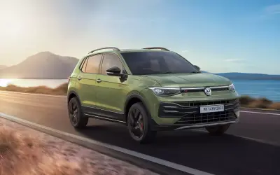 Volkswagen Taigun GT front three-quarter view in green, driving along a coastal road
