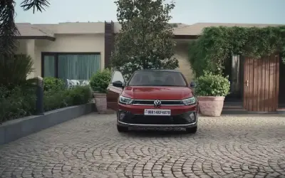 Volkswagen Virtus GT front view in red, parked on a cobblestone driveway