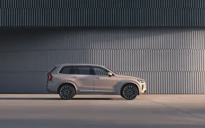 Volvo XC90 side profile in silver alongside a ribbed concrete wall
